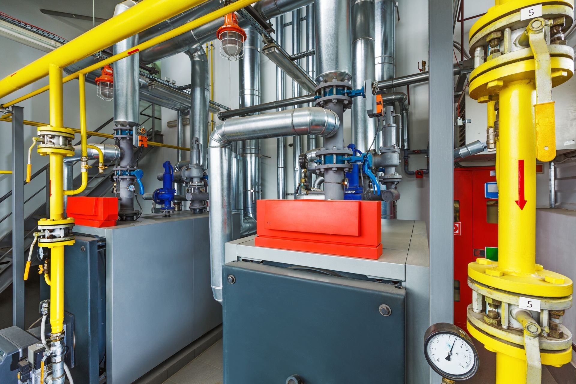 The interior of an industrial boiler house with a multitude of pipes, boilers and sensors.